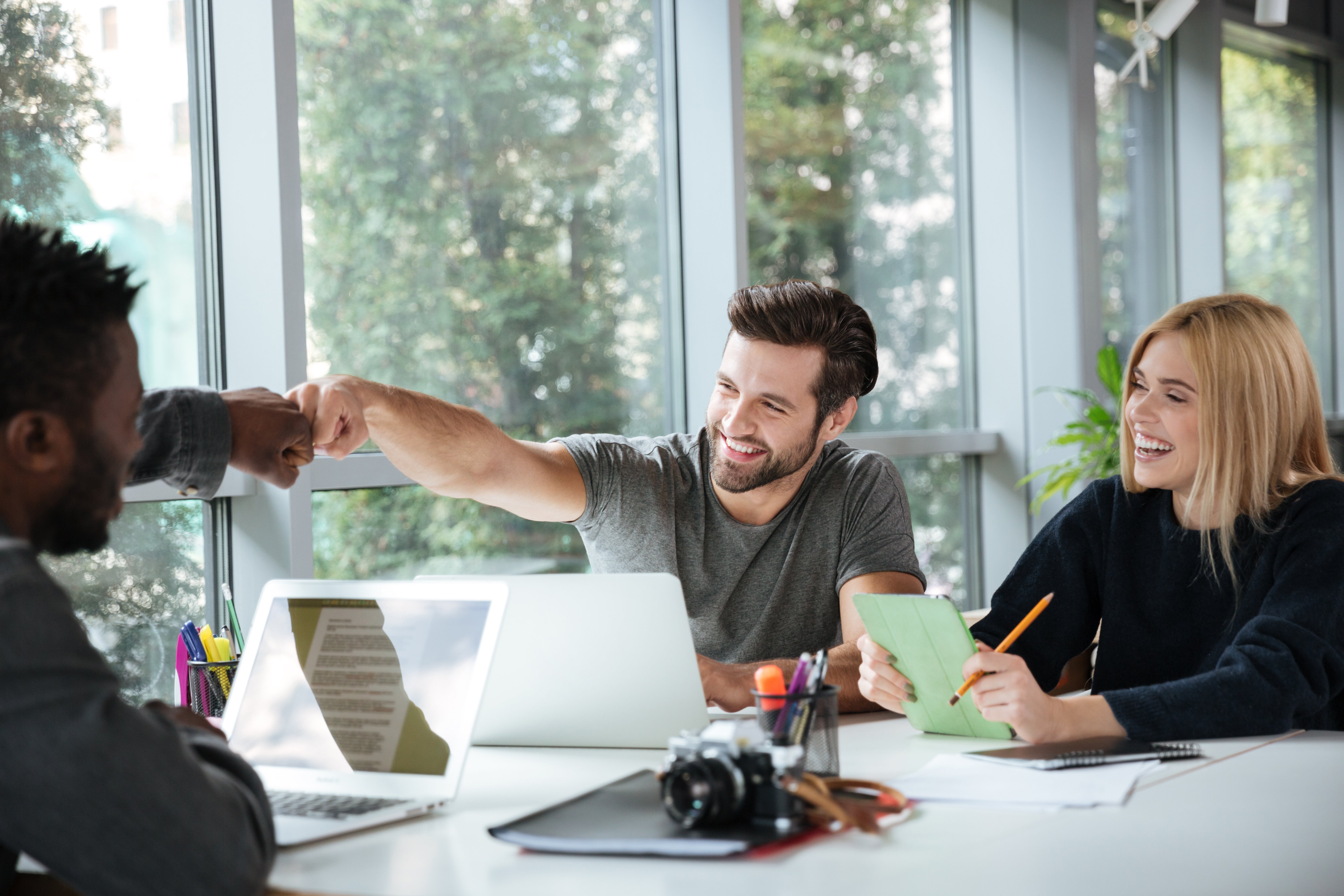 smiling-young-colleagues-sitting-office-coworking